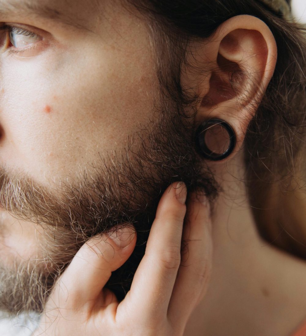 Close-up portrait of a man with a beard and earrings, showcasing personal style.